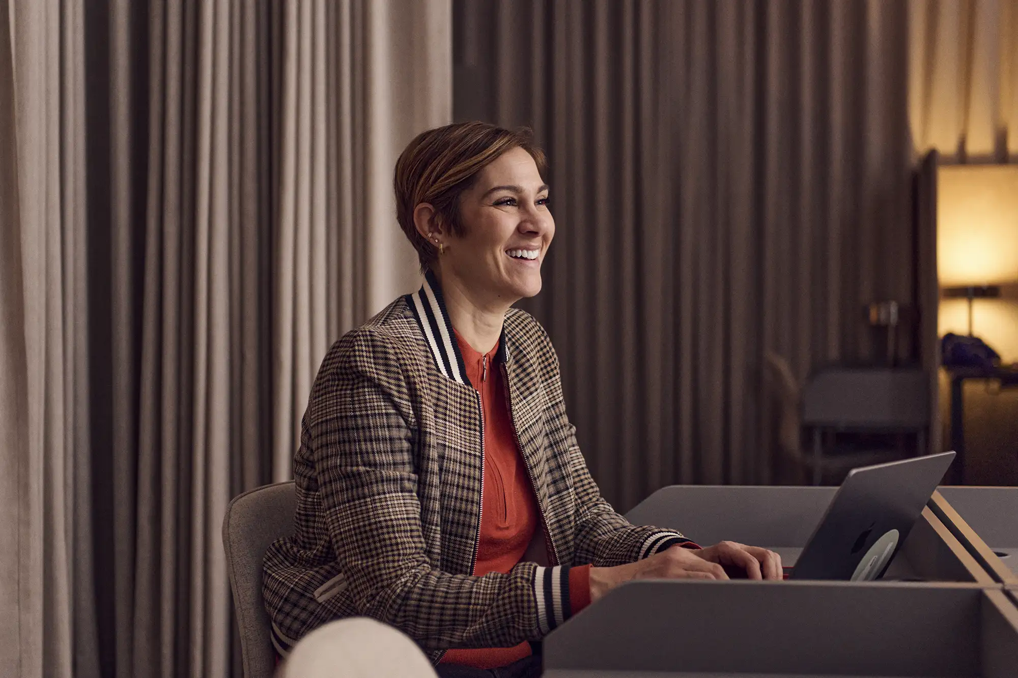 En leende medarbetare framför en laptop i ett mötesrum.