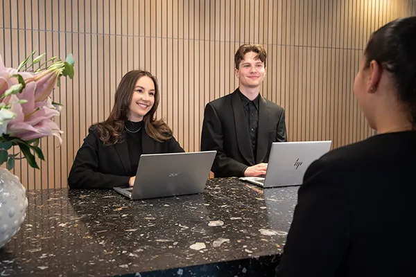 tv&aring; kontorsv&auml;rdar bakom en receptionsdisk p&aring; ett modernt kontor